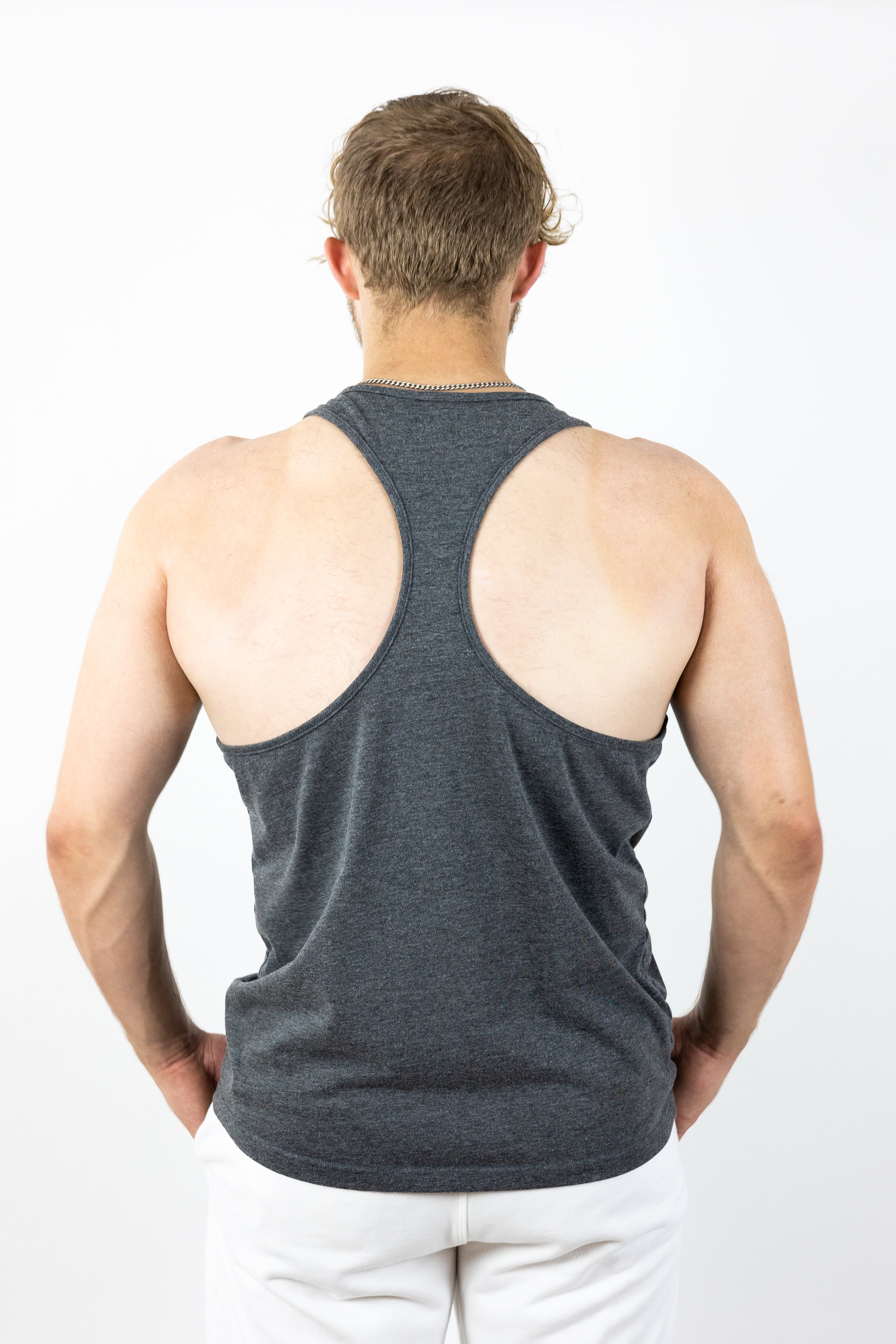 Back of man wearing gray stringer with hands in pockets of sweatpants