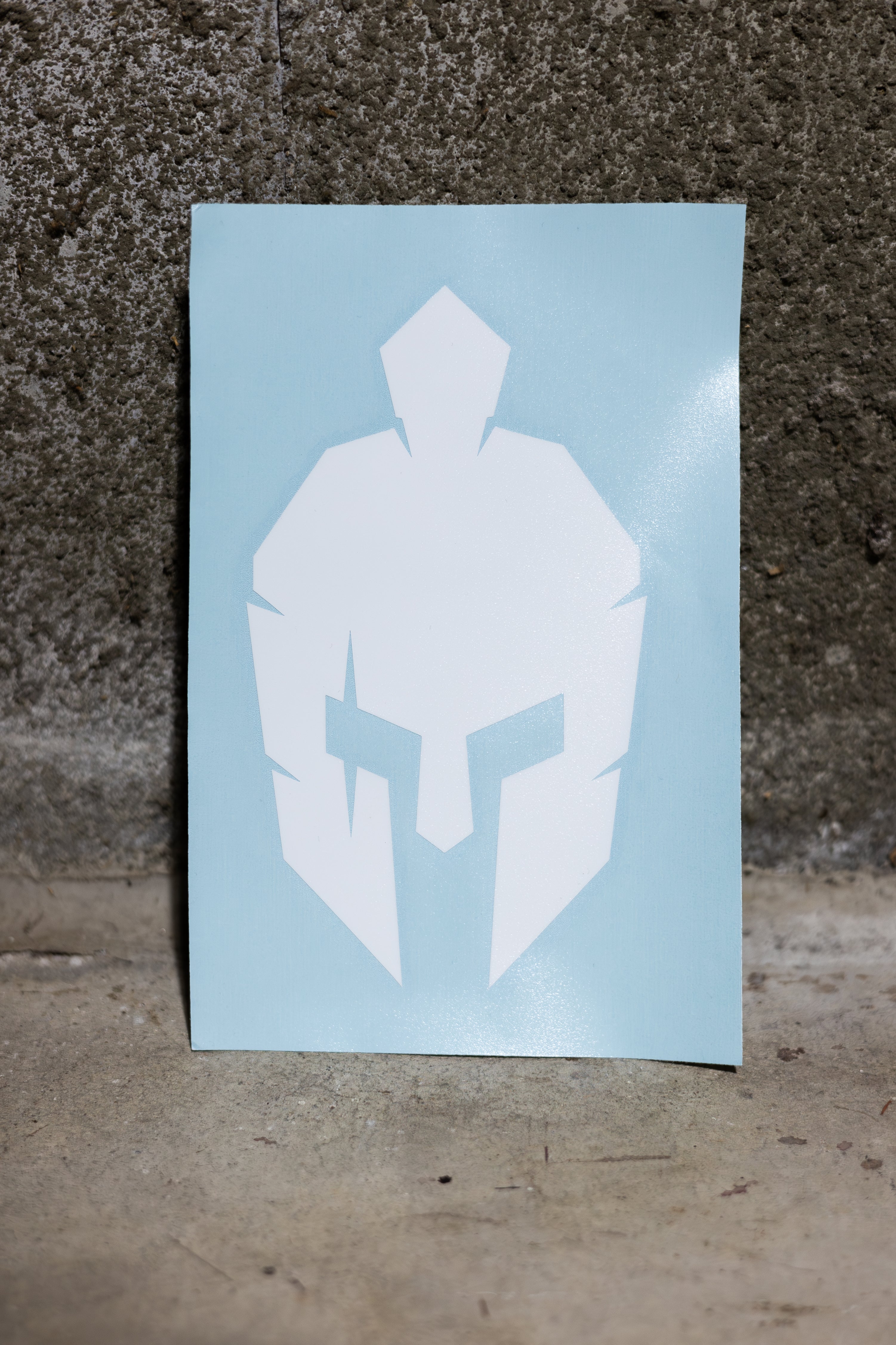 roman warrior helmet sticker on the floor leaning against concrete wall