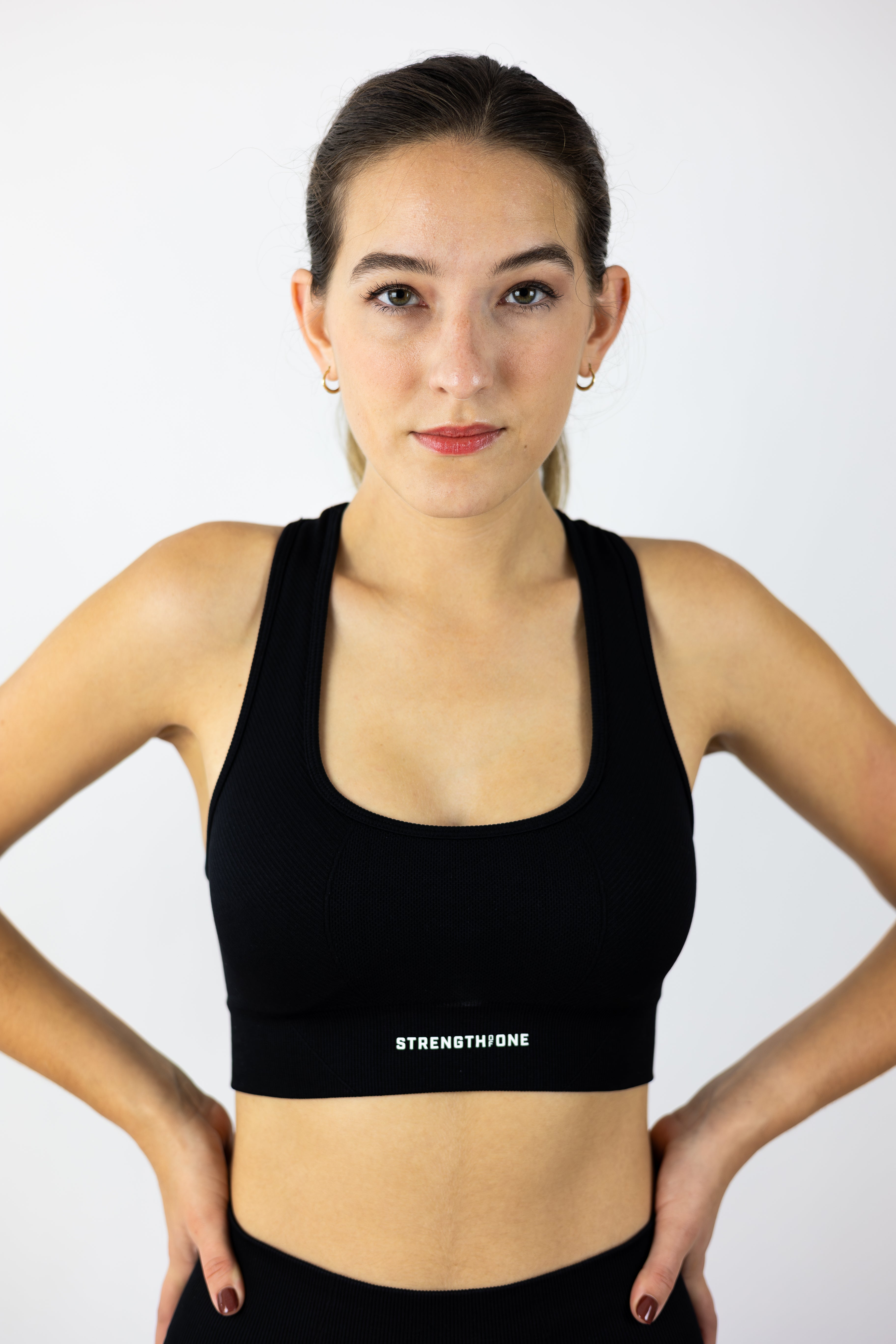 woman modeling Strength of One black sports bra with 3D raised logo on lower band
