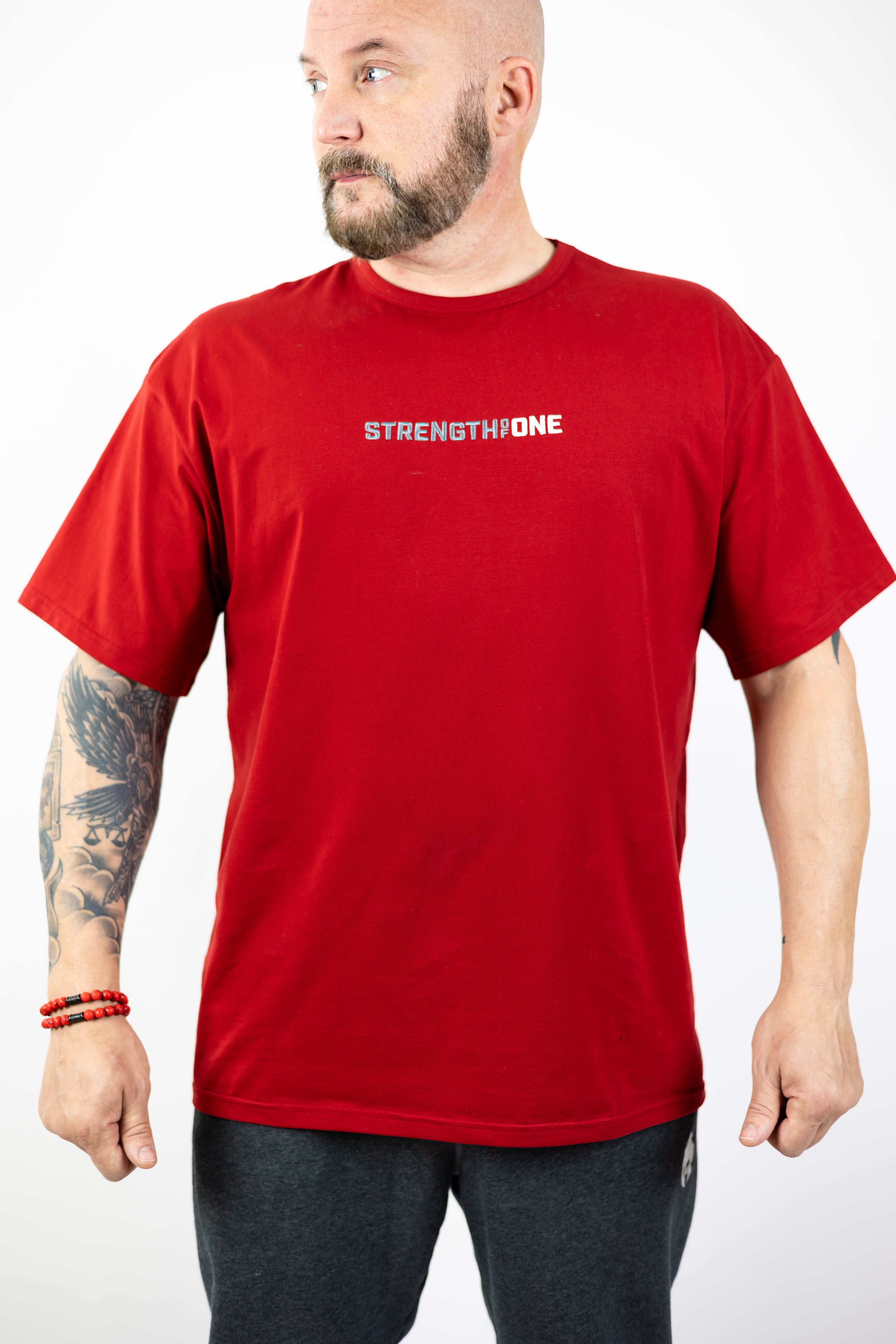 man modeling red Strength of One workout shirt with an embroidered logo reading Strength of One on the front chest