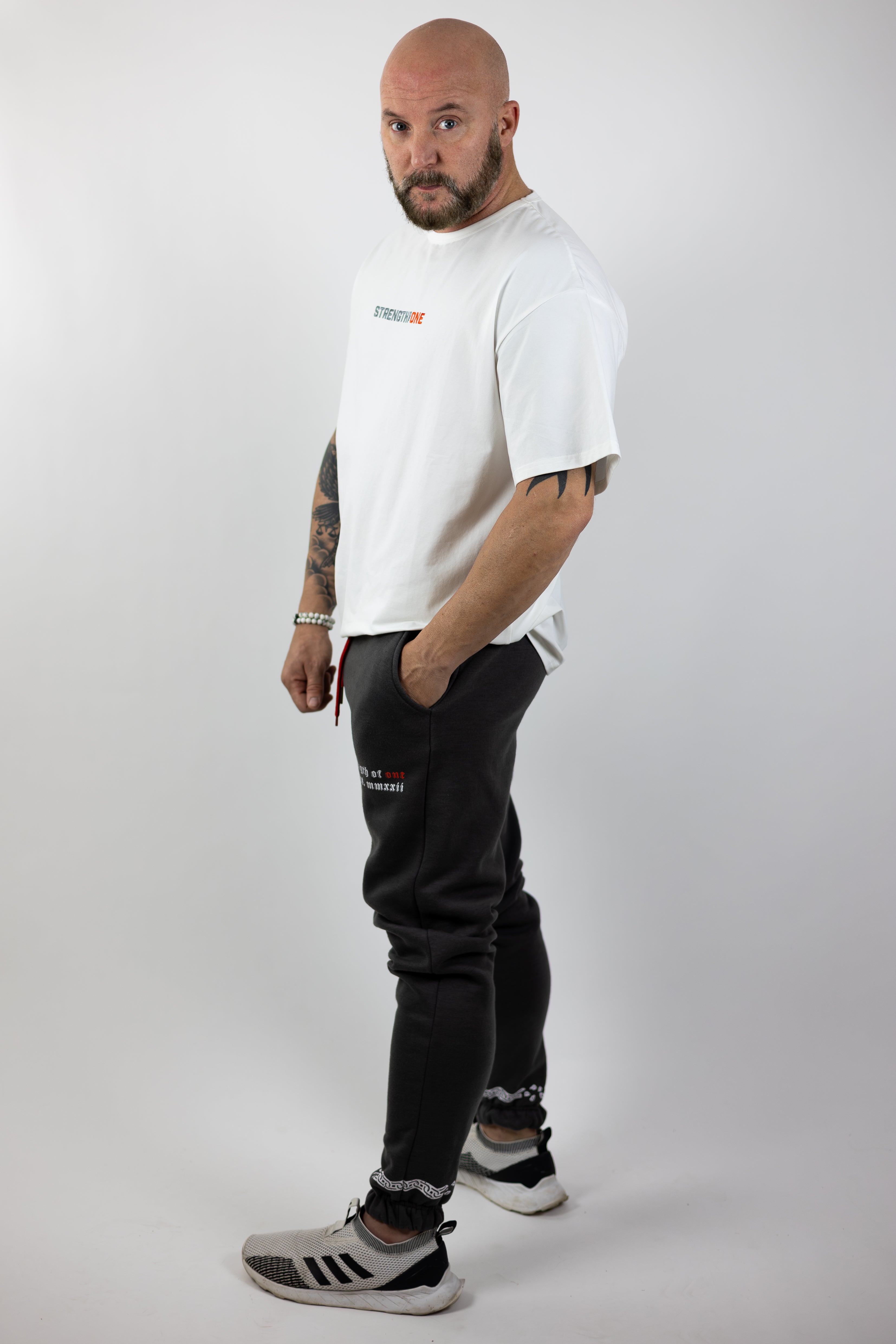 man wearing white Strength of One gym shirt and gray sweatpants