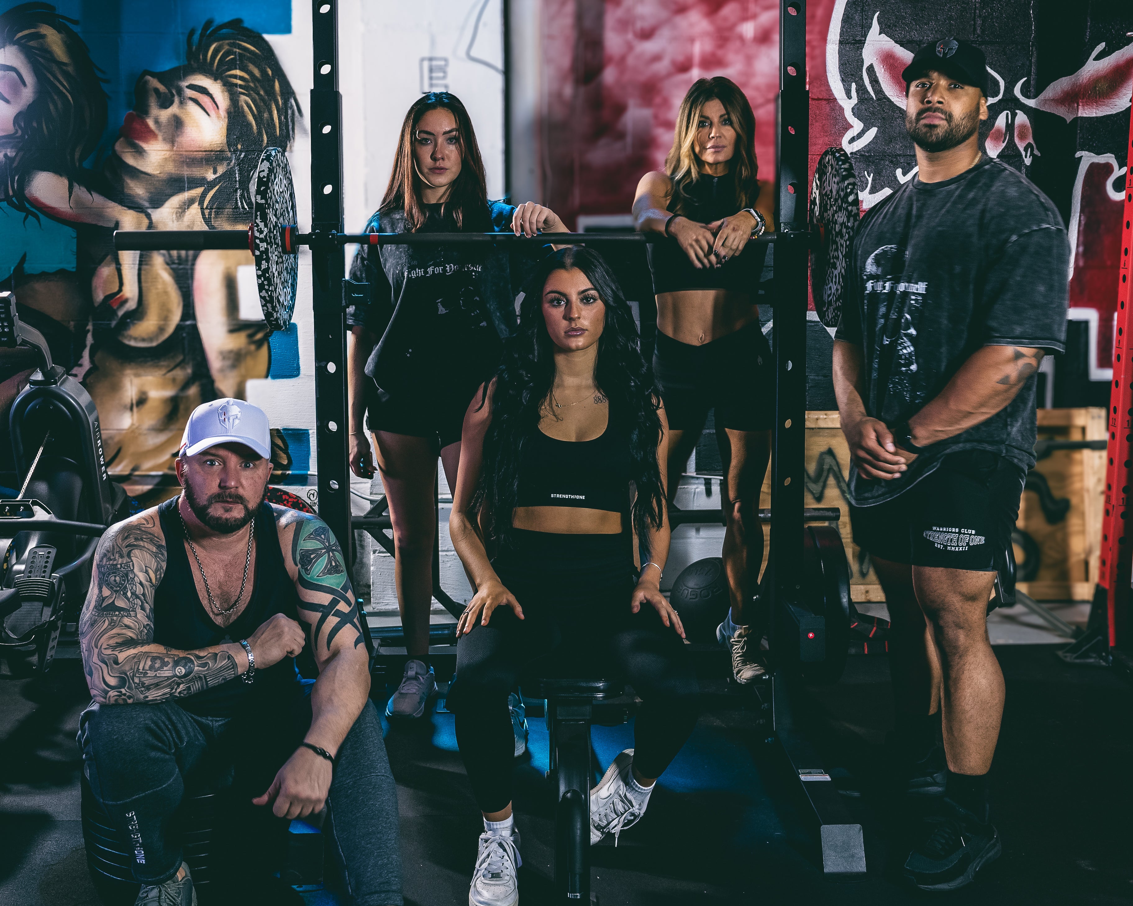 Strength of One models standing at a rack in the gym