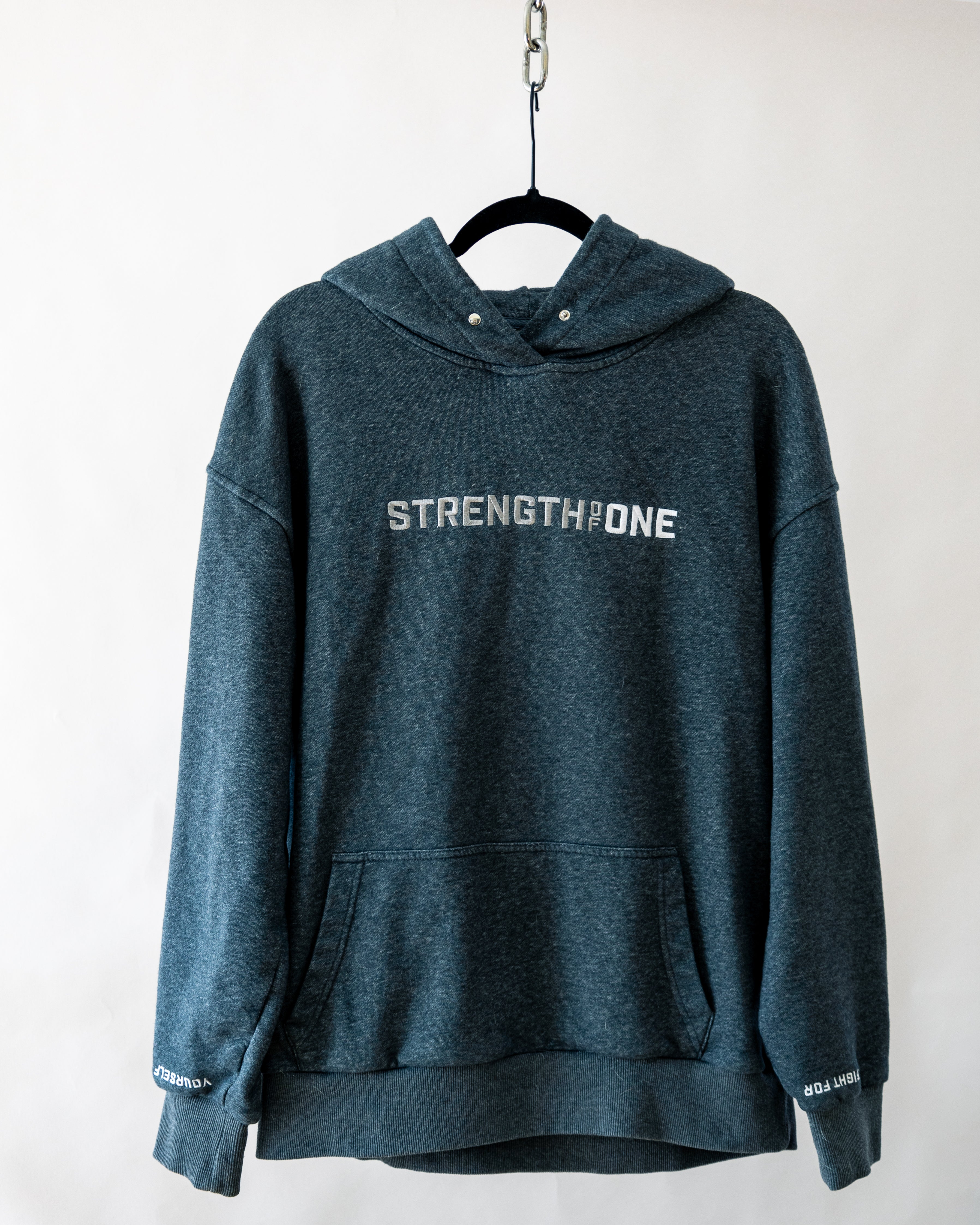 Gray Strength of One hoodie on hanger hanging by metal chain