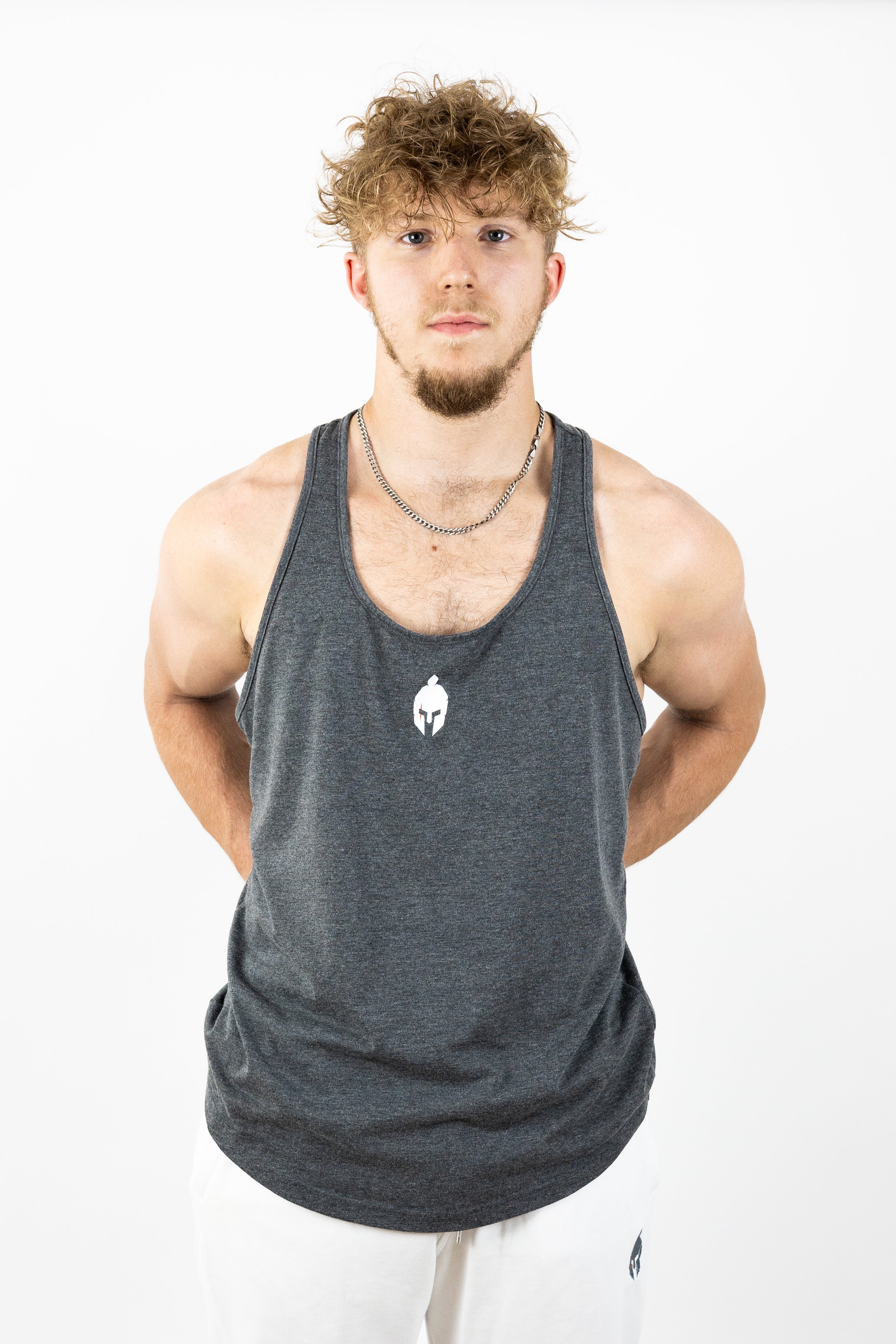 Man wearing gray stringer and silver chain with hands behind back