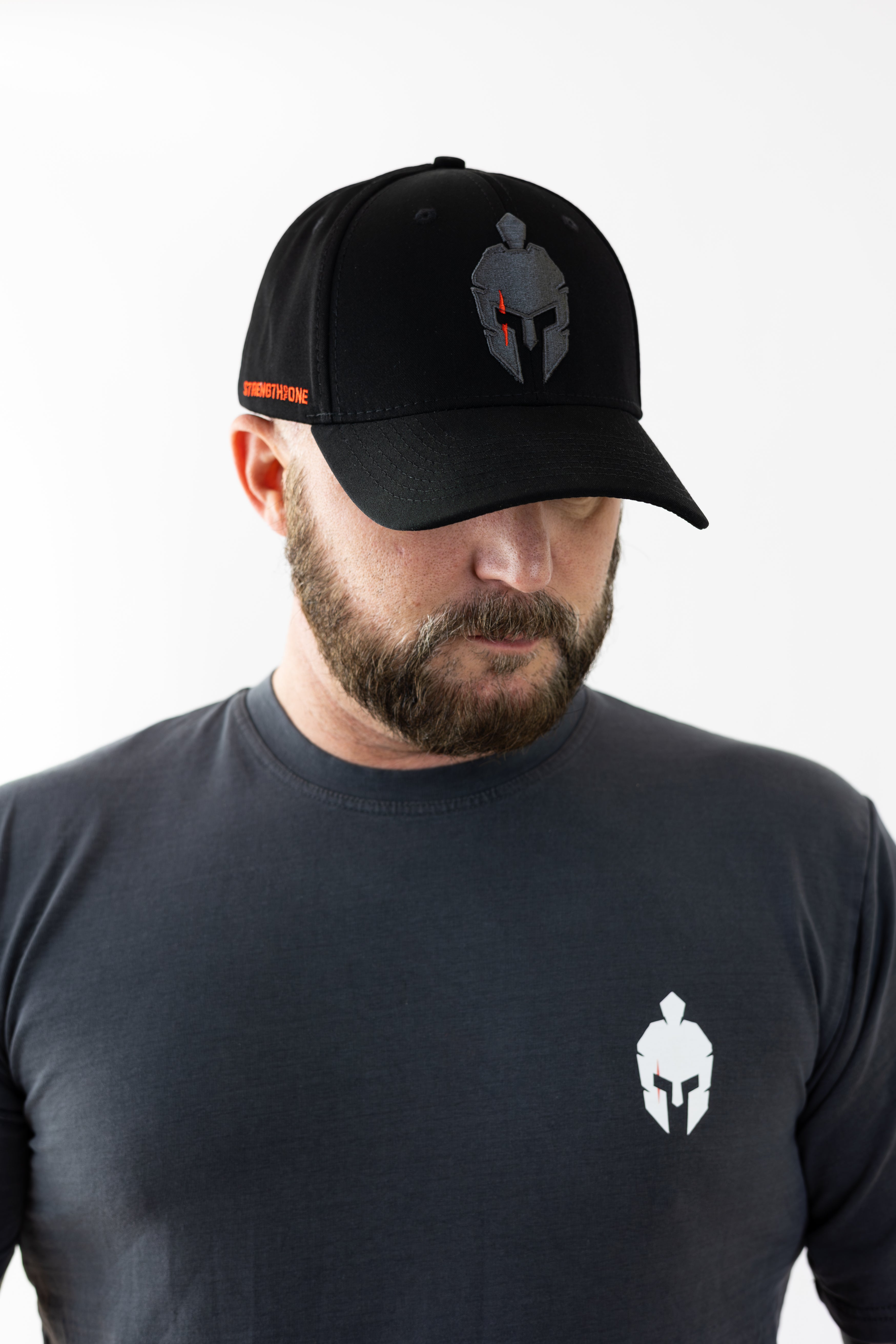Man wearing a black Strength of One cap and t-shirt with matching spartan warrior logos.
