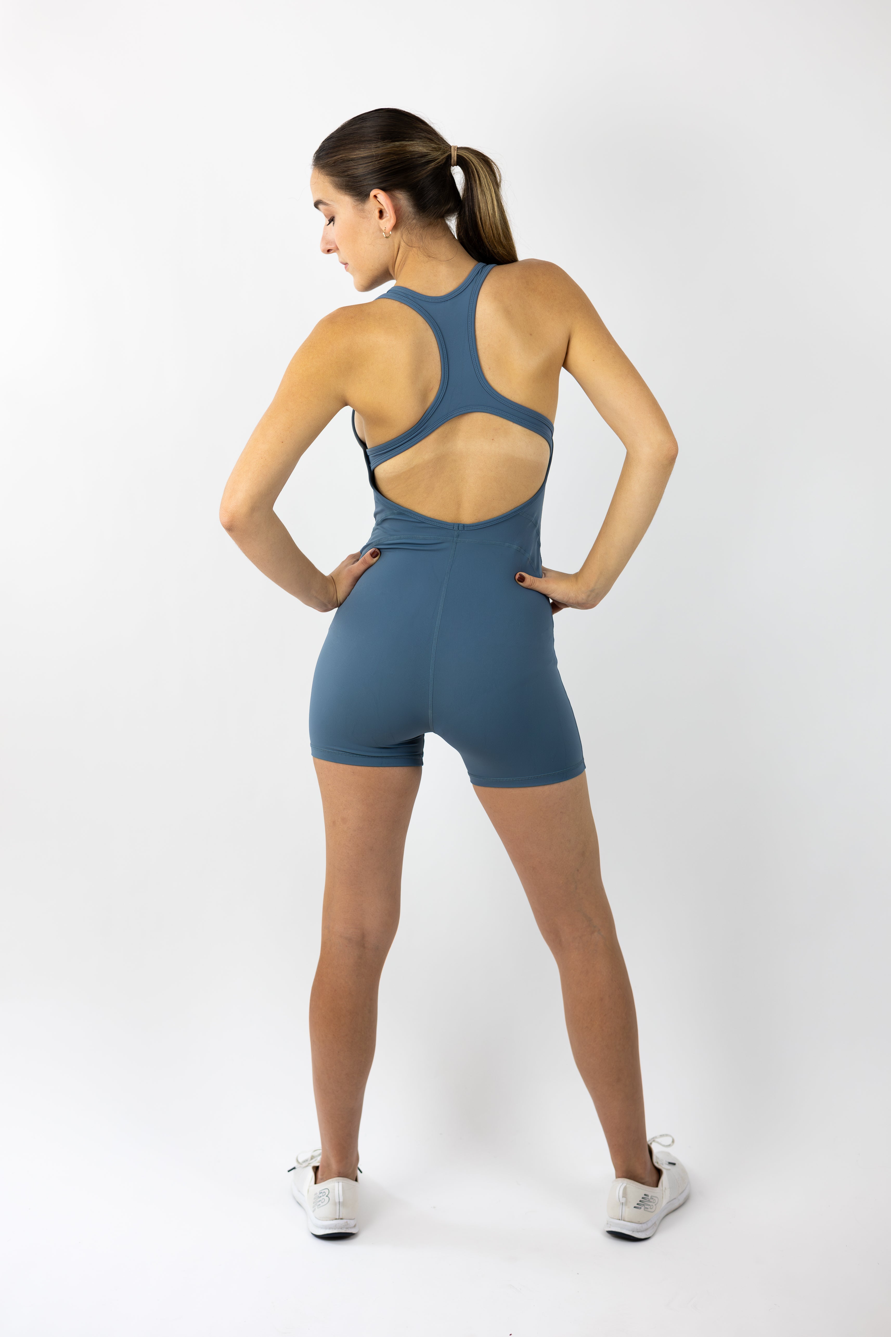 woman modeling light blue sports romper with helmet logo and lower right hip