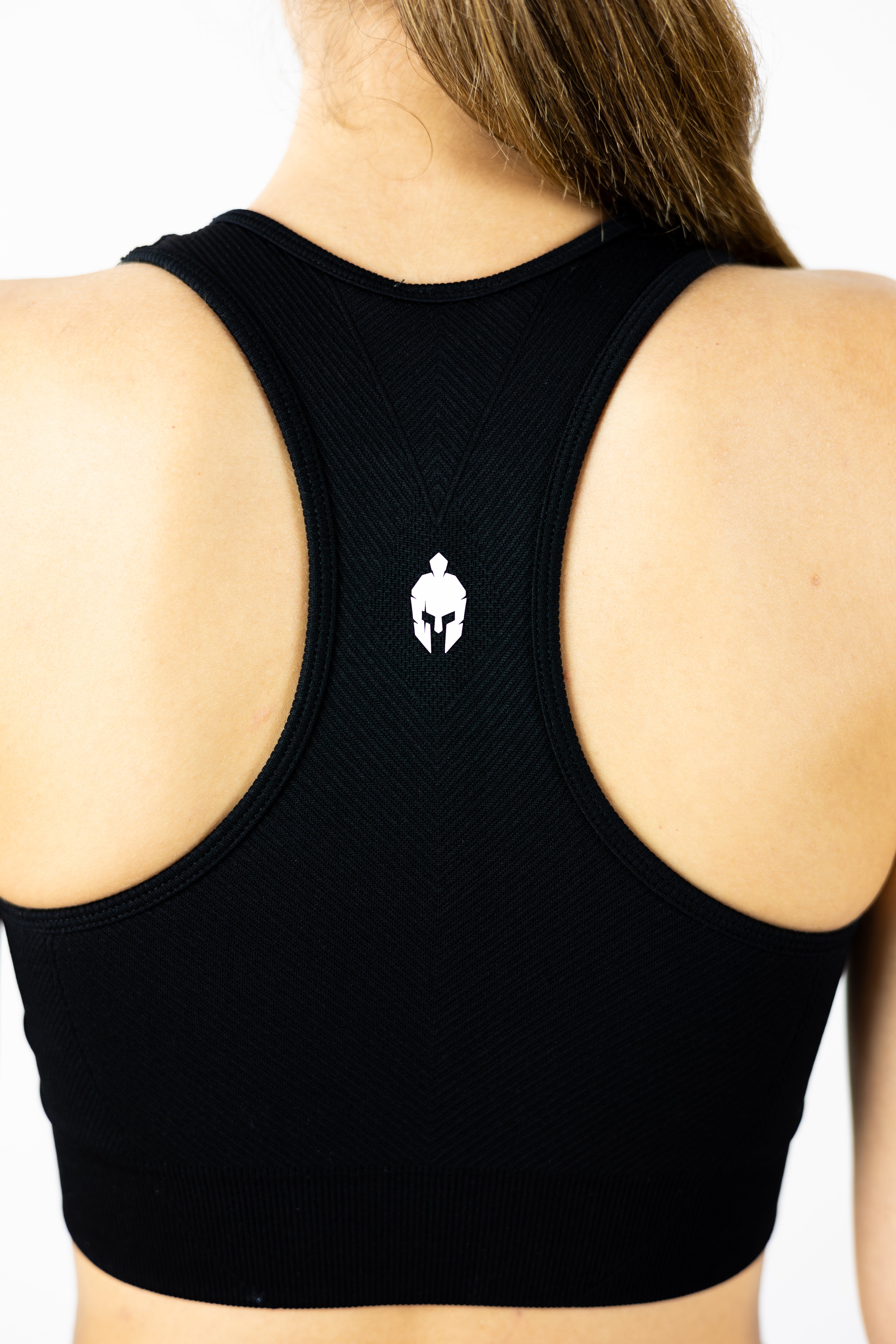 rear view of racerback style black Strength of One sports bra with spartan warrior logo between shoulders