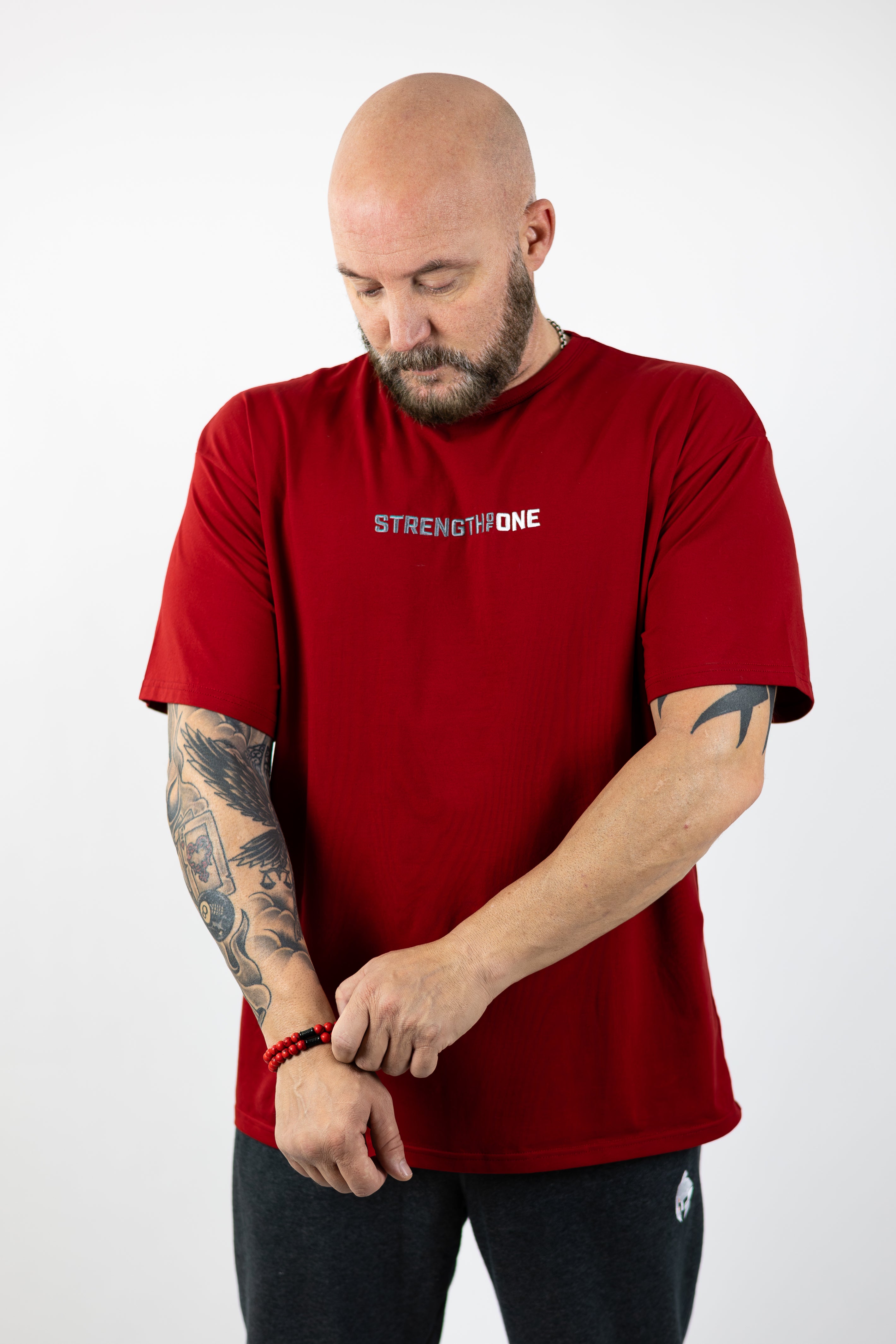 man modeling red Strength of One workout shirt with an embroidered logo reading Strength of One on the front chest