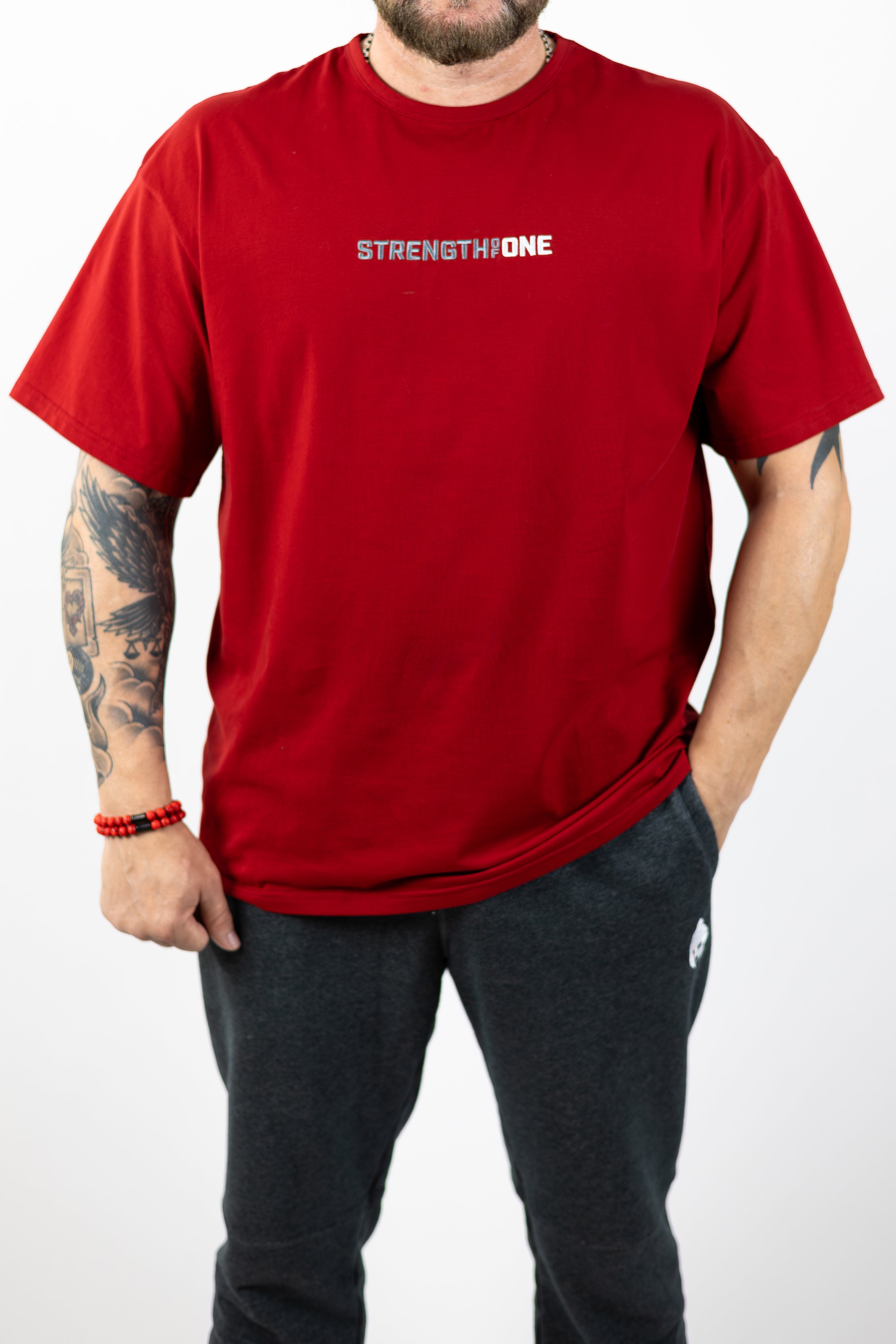 man modeling red Strength of One workout shirt with an embroidered logo reading Strength of One on the front chest