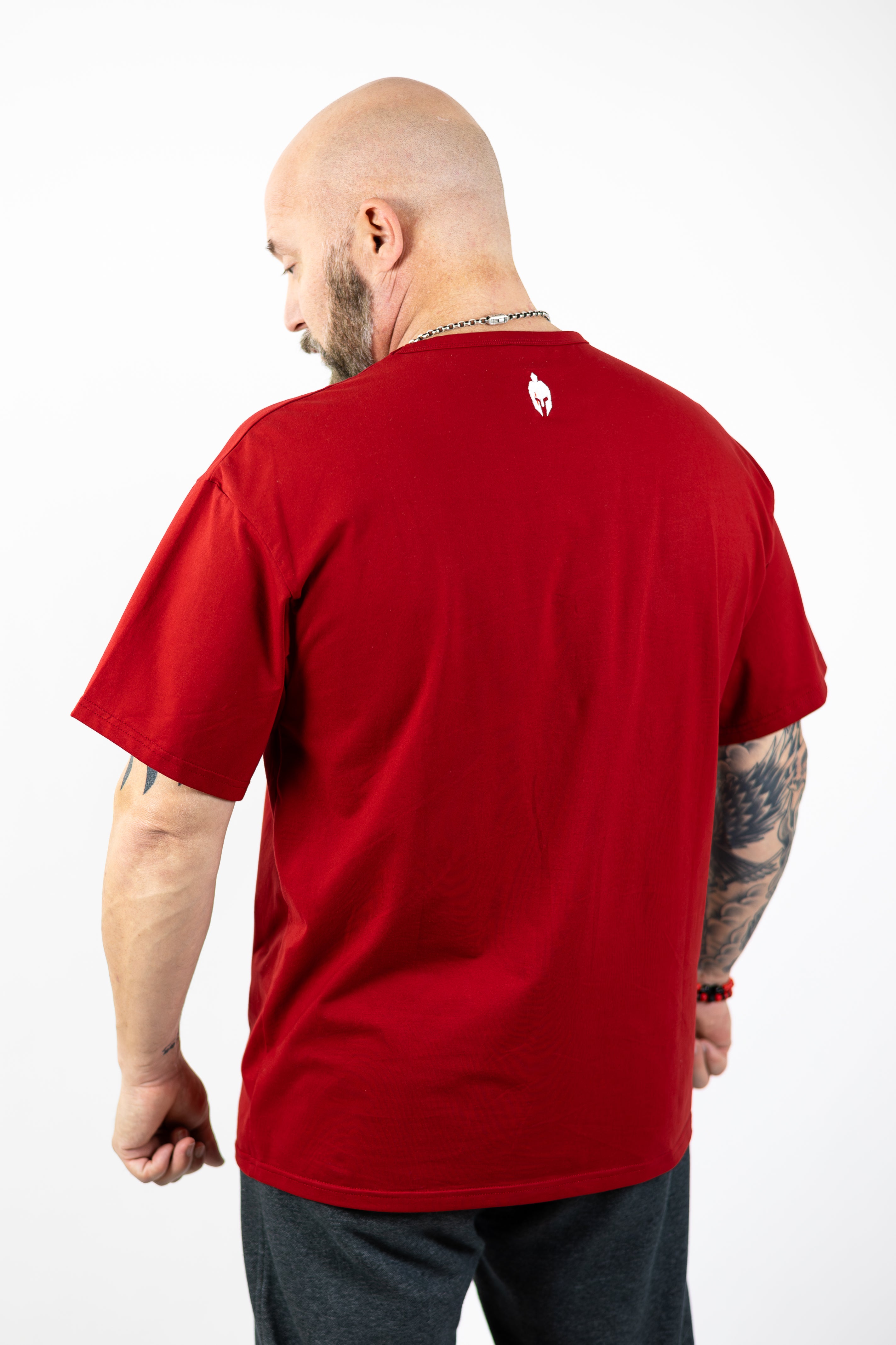 man modeling red Strength of One workout shirt with an embroidered helmet logo at the back neck