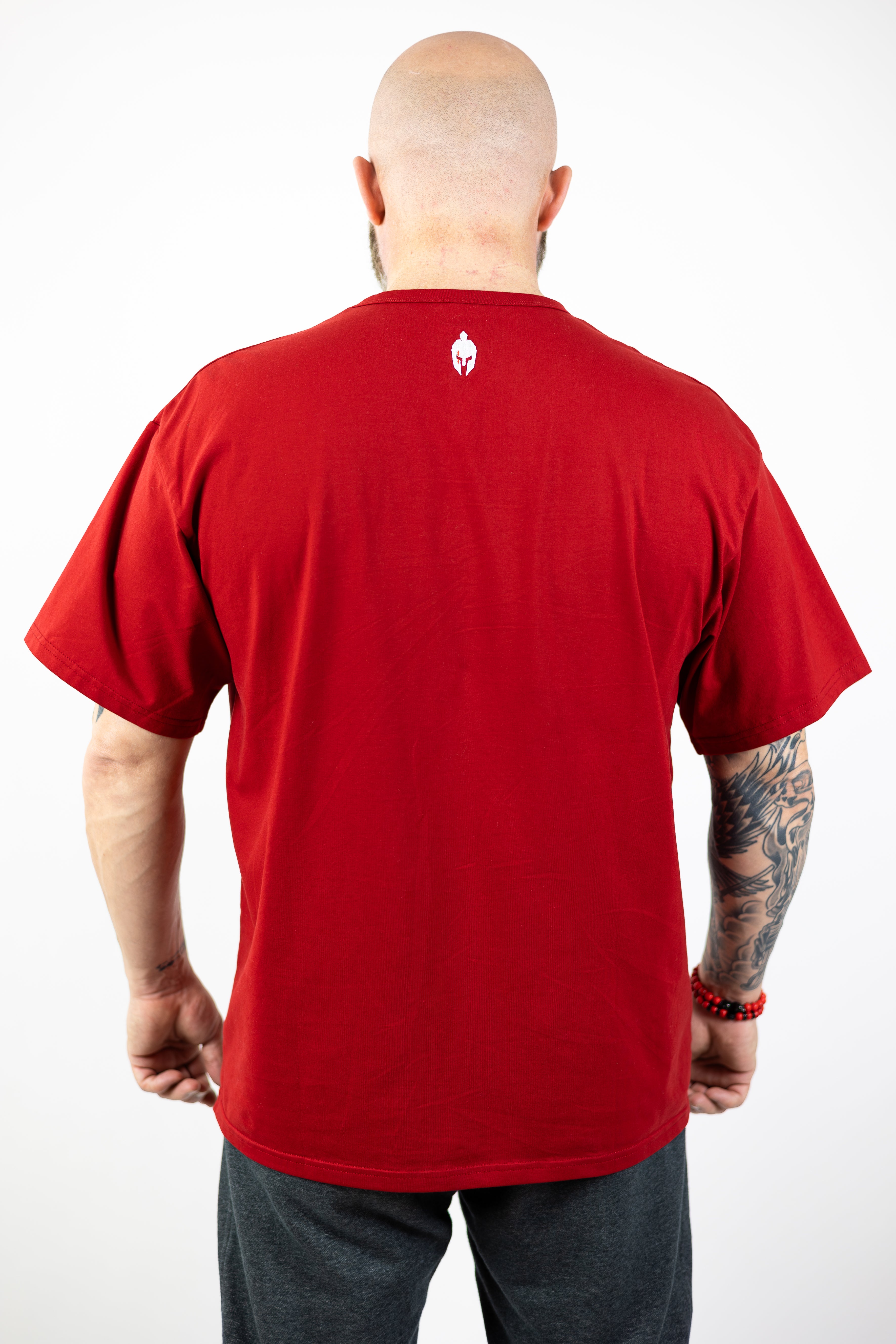 man modeling red Strength of One workout shirt with an embroidered helmet logo at back neck