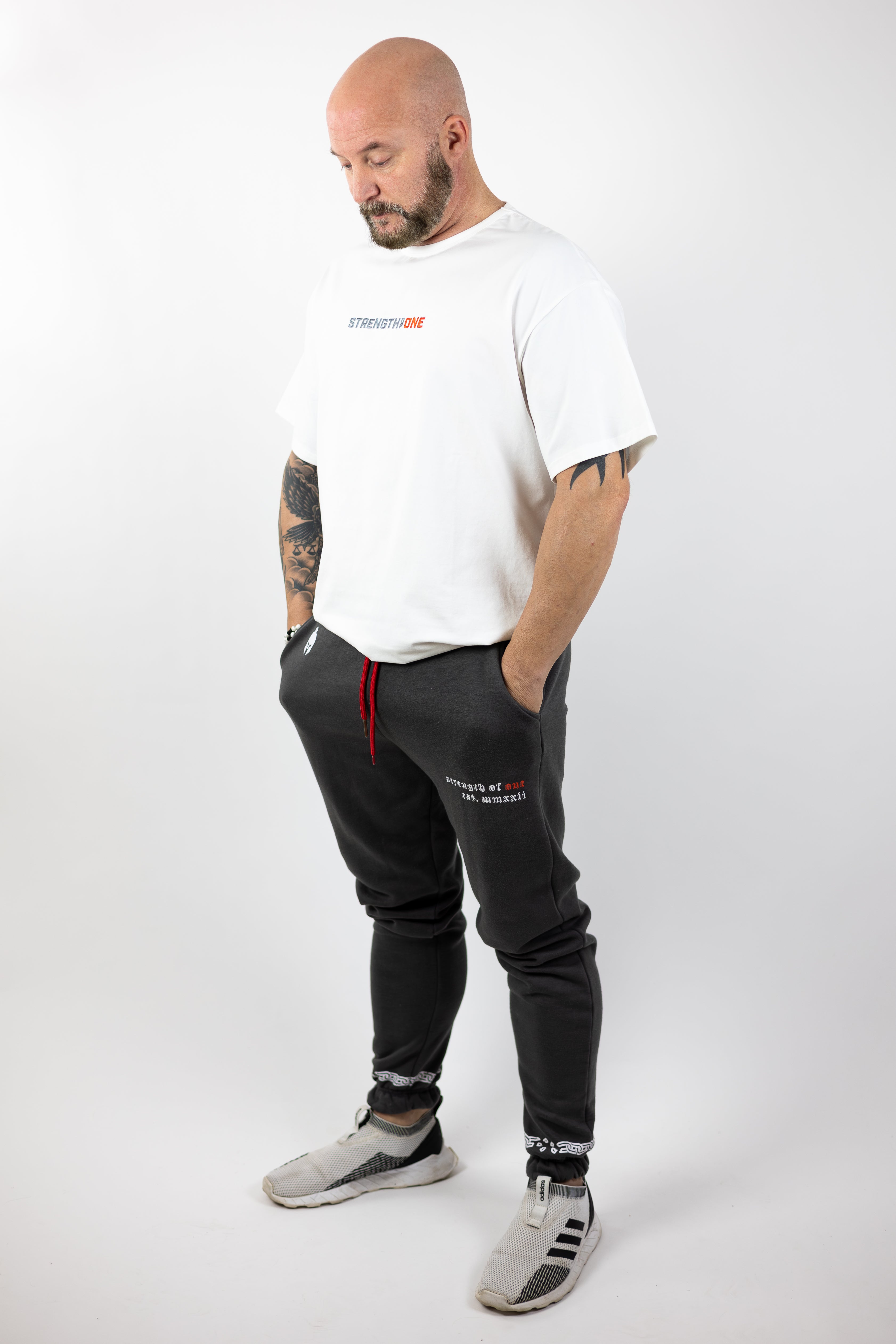 man modeling white Strength of One workout shirt with an embroidered logo reading Strength of One