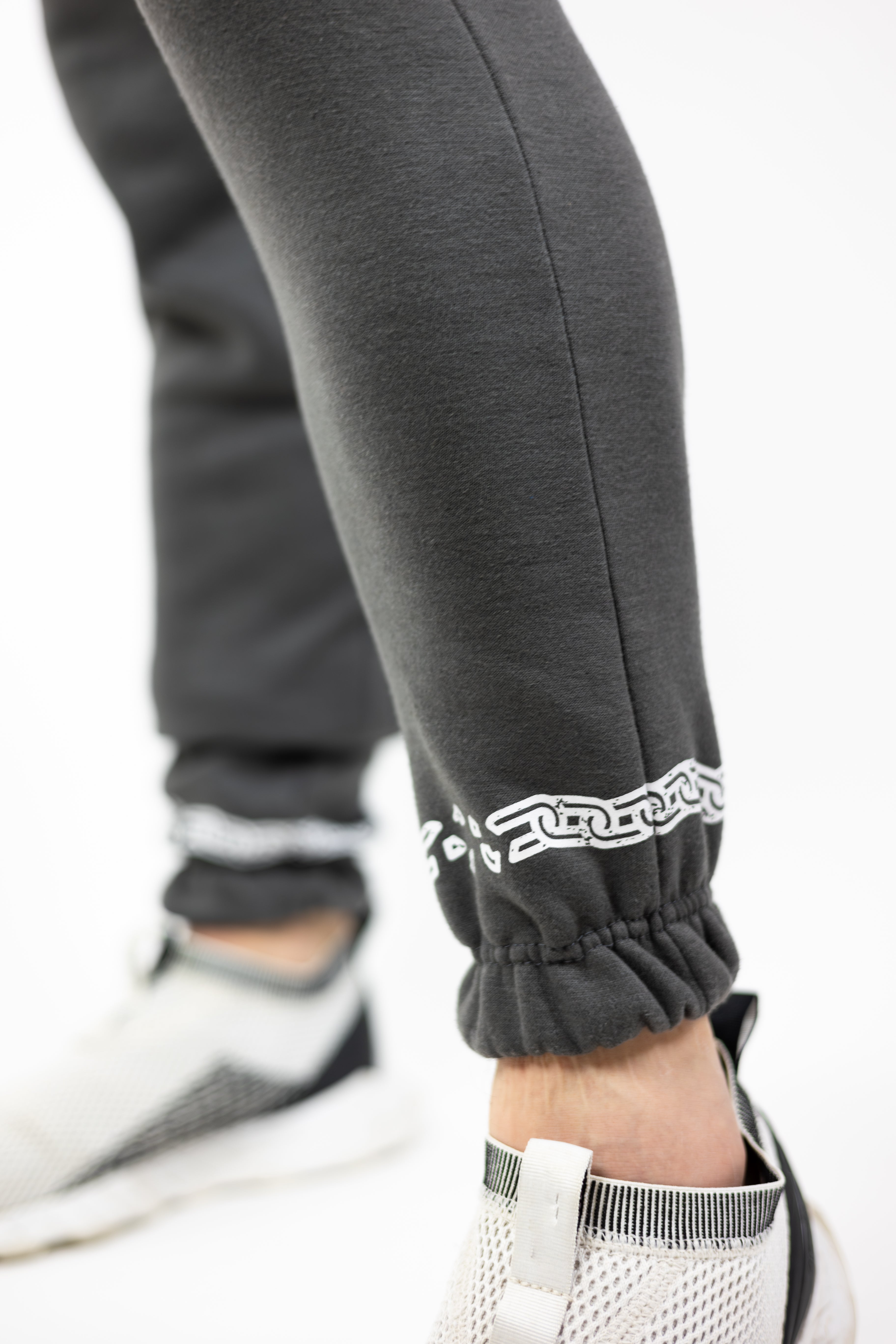 man wearing gray Strength of One sweatpants with white chain graphic going around ankle